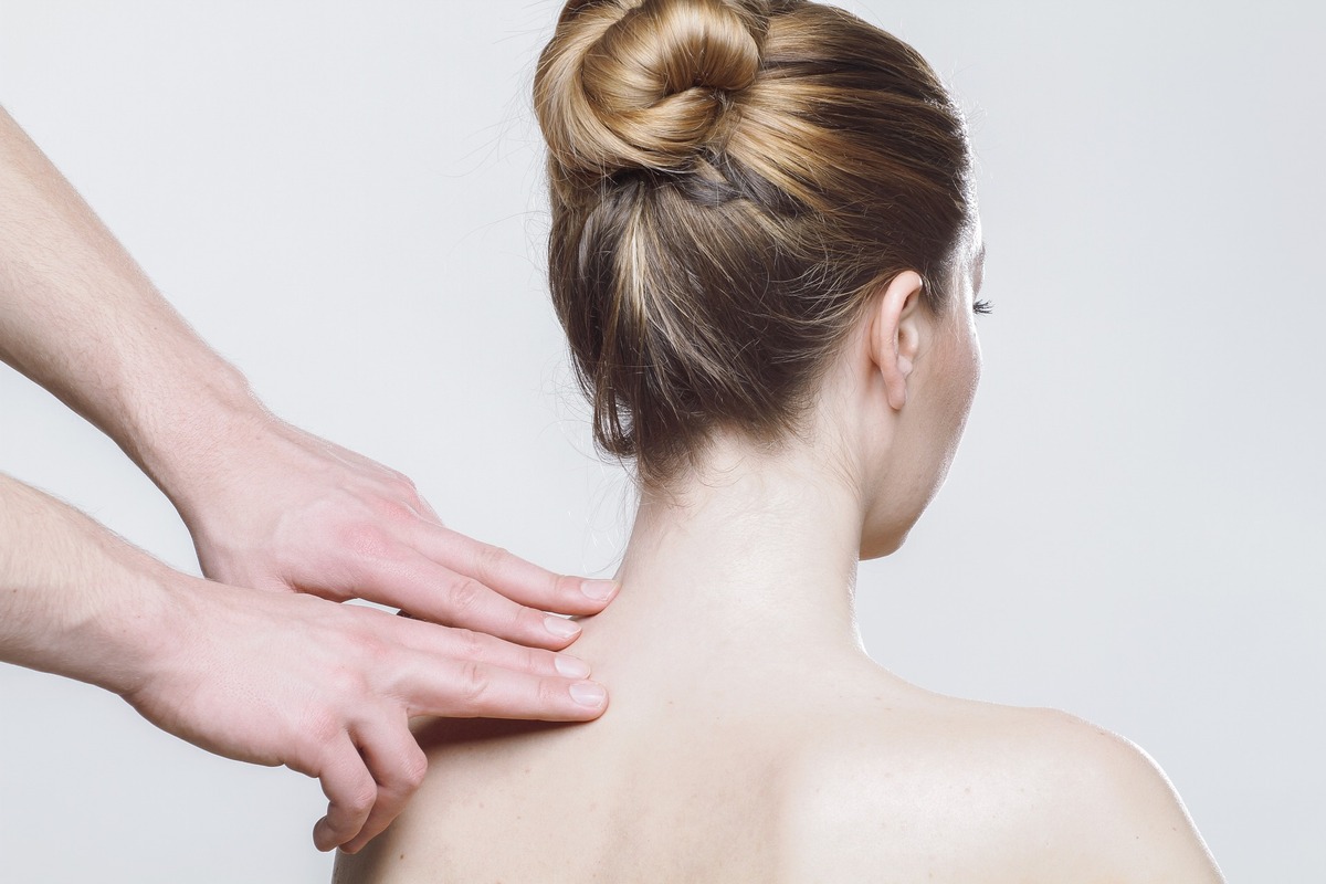 manos de terapeuta sobre espalda de mujer